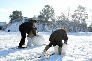 雪玉を作る親子。雪遊びは「５年前の大雪以来」という＝９日午前９時半ごろ、佐賀市の佐賀城本丸歴史館そば（撮影・円田浩二）