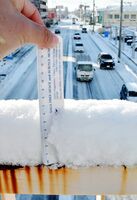 雪の影響で、車がゆっくりと走る国道２０８号。歩道橋の欄干の積雪を測ると約７センチだった＝９日午前８時５６分、佐賀市の新栄小前（撮影・米倉義房）