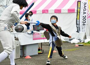 ＳＡＧＡ２０２４国スポ体験コーナーで、フェンシングにチャレンジする児童＝佐賀市文化会館前