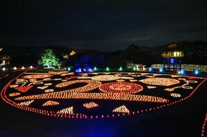 紙灯籠６０００個が描く地上絵。「２０ｔｈ」の字の上にはマスコットキャラクター「ひみか」（中央）と「やよい」（右）が並んでいる＝吉野ケ里歴史公園