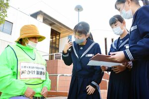 訓練で名前やけががないか聞き、社会福祉協議会に電話する中学生たち＝吉野ヶ里町中央公民館前