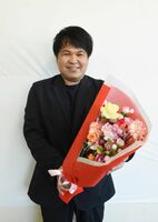 卒業生に花束を贈るＣＦを始めるクラベル・ジャパンの平田憲市郎社長。手にしているのは、５千円の寄付でもらえる返礼品の花束＝唐津市役所