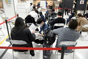 　海外から到着し、検疫のスタッフ（手前中央）から必要書類や滞在地などの確認を受ける旅客＝１日午後、成田空港