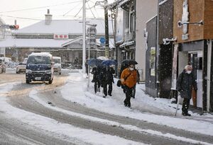 雪で滑らないように気をつけながら、職場へと急ぐ通勤者ら＝１８日午前７時４５分ごろ、鳥栖市京町