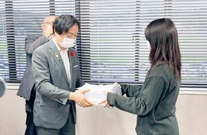 １８歳成人式で高校生から署名を受け取る三重県伊賀市の岡本栄市長（左）＝１０月、同市役所
