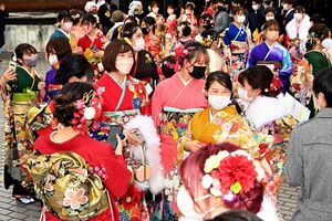 色鮮やかな晴れ着姿で、マスクを付けたまま友人との再会を喜ぶ新成人たち＝９日、佐賀市文化会館
