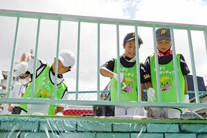 はけやローラーで丁寧に柵を塗装する若楠少年野球の子どもたち＝佐賀市の若楠地下道