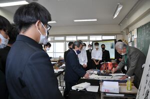 生徒たちに囲まれながら、書をしたためる米倉さん＝佐賀市の佐賀西高