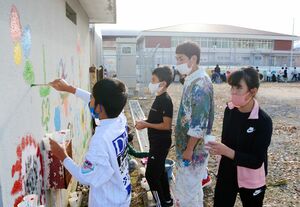 ＳＨＯＧＥＮさん（右から２人目）と壁に絵を描く子どもたち＝鹿島市の鹿島小