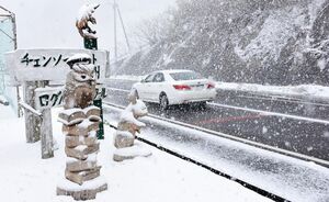 雪が吹雪く中、スリップしないように低速で走行する乗用車＝佐賀市大和町松瀬付近