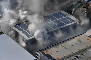 　２日目になっても煙を上げる日立物流西日本の倉庫＝３０日午前、大阪市（共同通信社ヘリから）